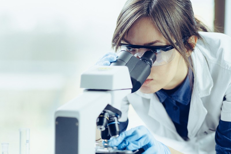 scientist looking through microscope